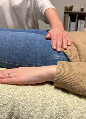 Mains posées sur le ventre d'une personne allongée pendant un soin