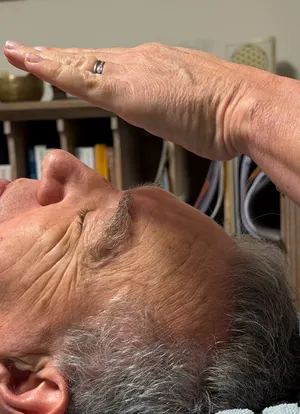 Imposition des mains au-dessus du visage pendant une séance de Reiki