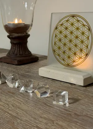 Solides de Platon en cristal devant une fleur de vie dorée et une bougie